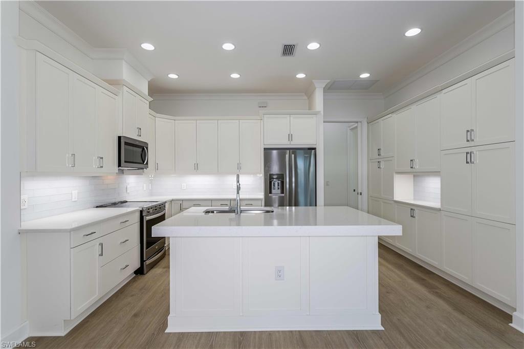 9004 Calypso Court Naples, FL 34113 - Photo 4 of 44 a kitchen with kitchen island a sink a stove a refrigerator and white cabinets