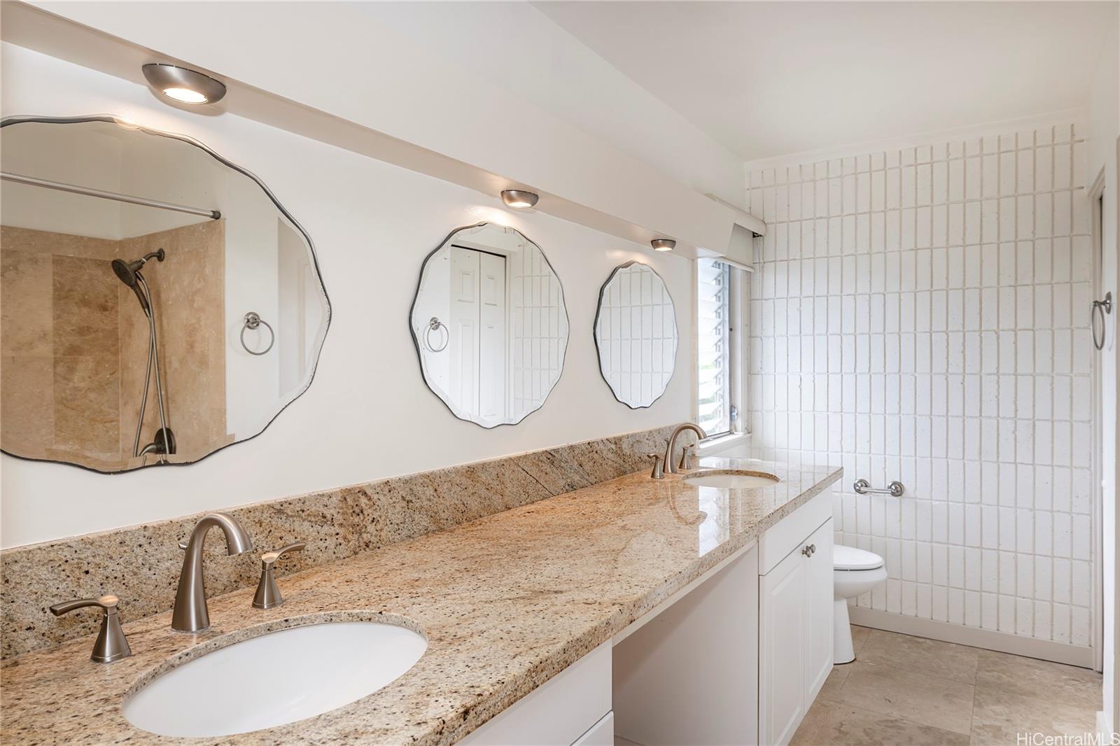 404 Koko Isle Circle, Unit 1802 Honolulu, HI 96825 - Photo 9 of 18 a bathroom with a granite countertop double vanity sink and a mirror