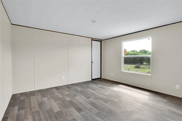 a view of an empty room with a window and wooden floor