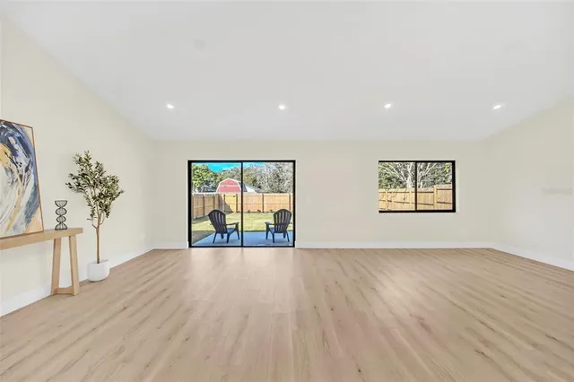a view of an empty room with a window and wooden floor