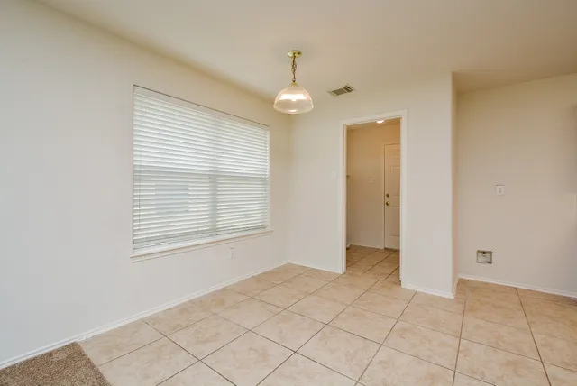 a view of an empty room with window and chandelier fan