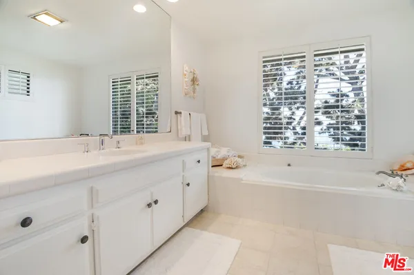 a bathroom with a bathtub a sink a vanity and a large mirror