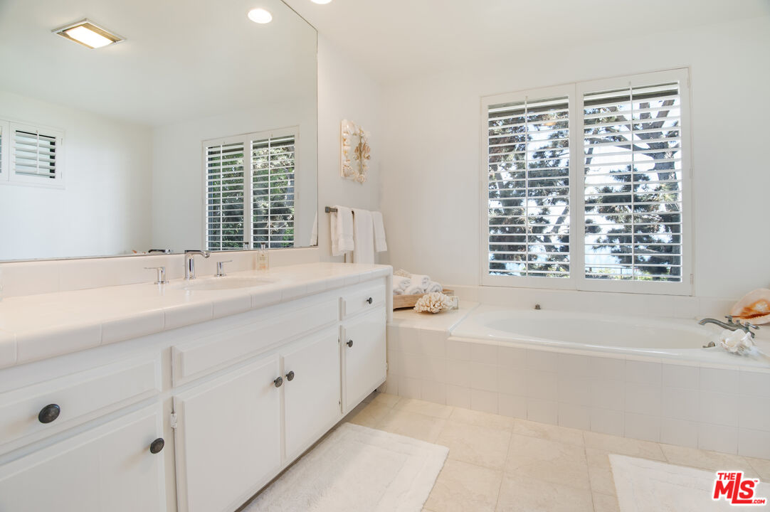29008 Cliffside Drive Malibu, CA 90265 - Photo 21 of 28 a bathroom with a bathtub a sink a vanity and a large mirror