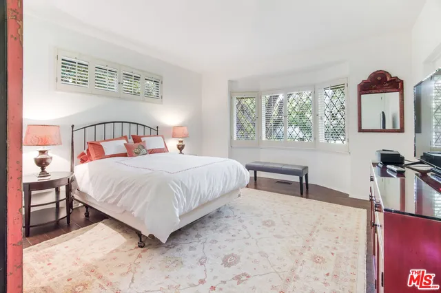 a bedroom with a bed and a dresser with mirror