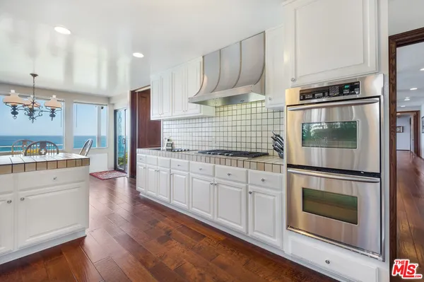a kitchen with stainless steel appliances white cabinets and wooden floors