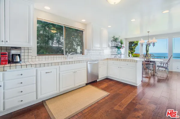 a kitchen with white cabinets and wooden floors
