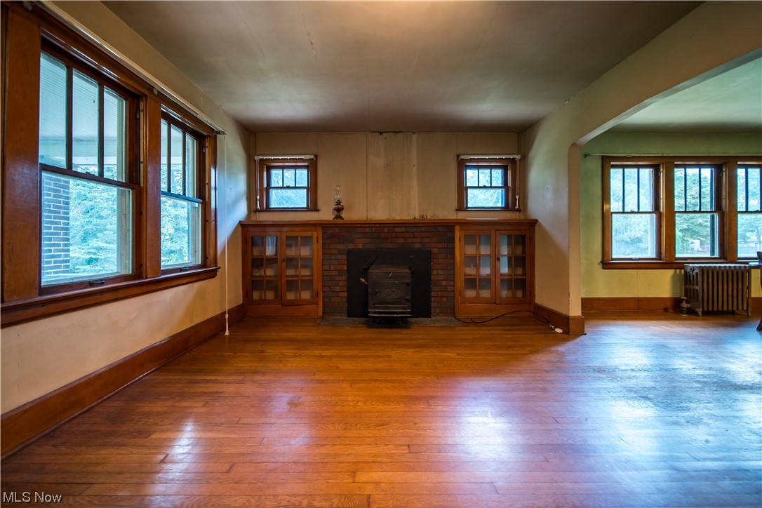 Hardwood floored living room featuring a fireplace and radiator