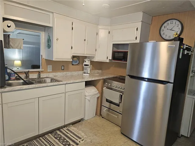 a kitchen with stainless steel appliances granite countertop a refrigerator a sink a stove and white cabinets