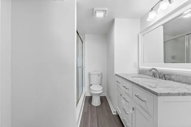 a bathroom with a granite countertop double vanity sink a mirror and a toilet