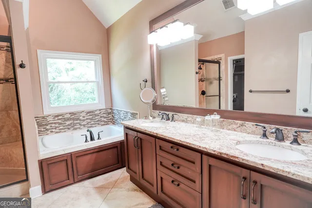 a bathroom with a granite countertop double vanity sink and mirror with window