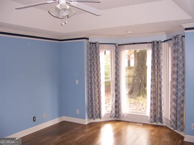 a view of an empty room with a window and wooden floor