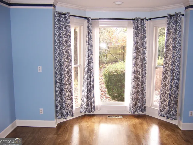 a view of an empty room with a window and hardwood floor