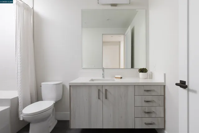 a spacious bathroom with a double vanity sink a toilet and a mirror
