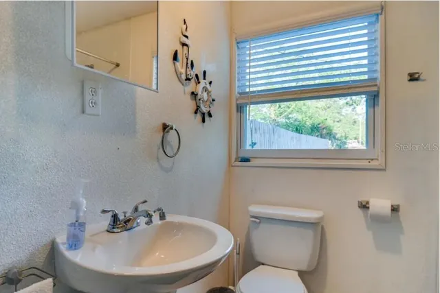 a bathroom with a toilet a sink and a window