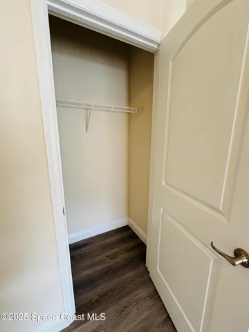 an empty room with wooden floor chandelier fan and windows