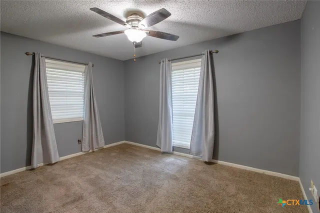 an empty room with windows and fan