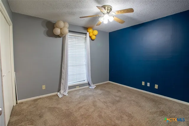 an empty room with windows and fan