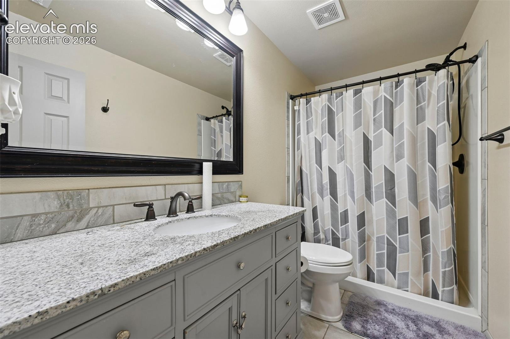 8347 Tibbs Road Peyton, CO 80831 - Photo 10 of 38 Bathroom vanity featuring a light-toned countertop, under-mount sink, and dark bronze-finish faucet