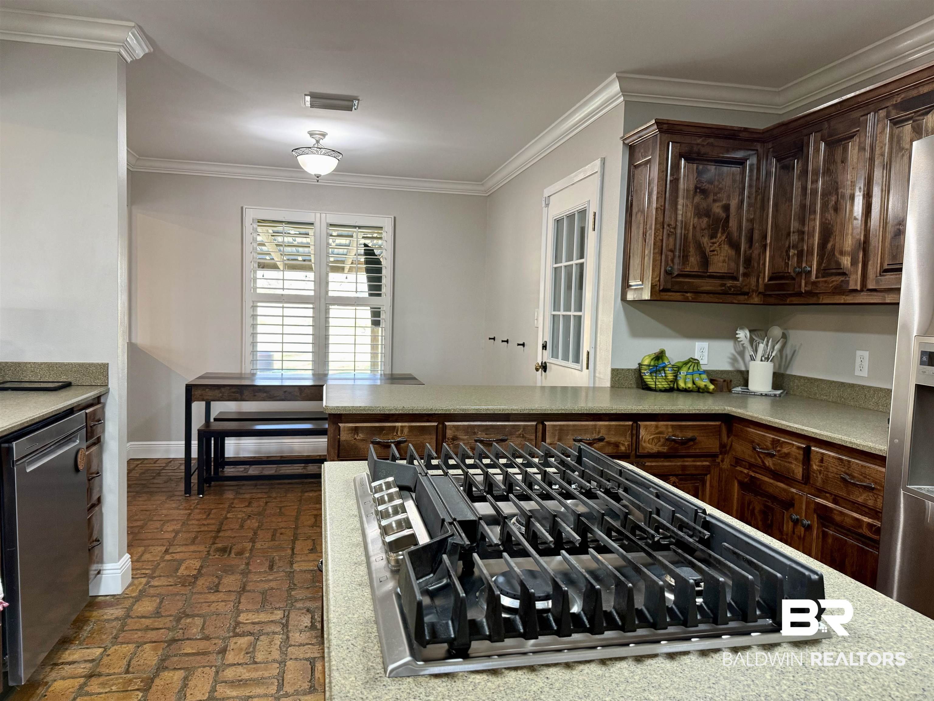 5646 Foshee Road Brewton, AL 36426 - Photo 8 of 37 Kitchen featuring stainless steel appliances, dark wood finish cabinets, brick flooring, ornamental molding, and light stone counters