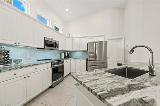 a kitchen with stainless steel appliances granite countertop a sink and white cabinets