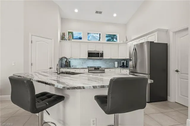 a kitchen with stainless steel appliances granite countertop a refrigerator a stove a sink and white cabinets