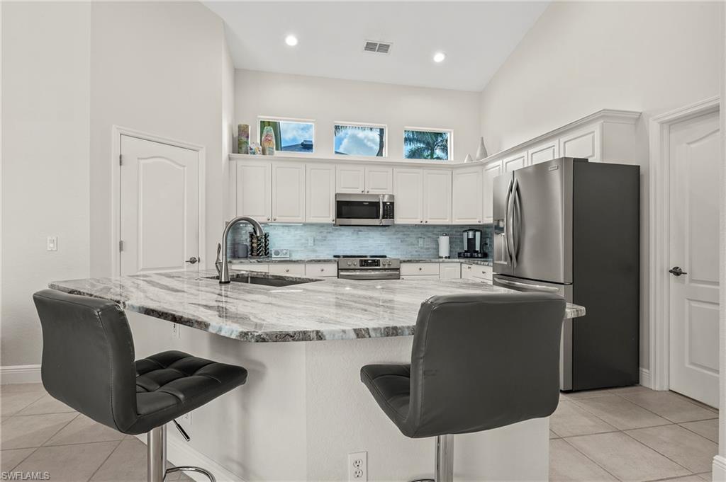 2039 Terrazzo Lane Naples, FL 34104 - Photo 5 of 29 a kitchen with stainless steel appliances granite countertop a refrigerator a stove a sink and white cabinets