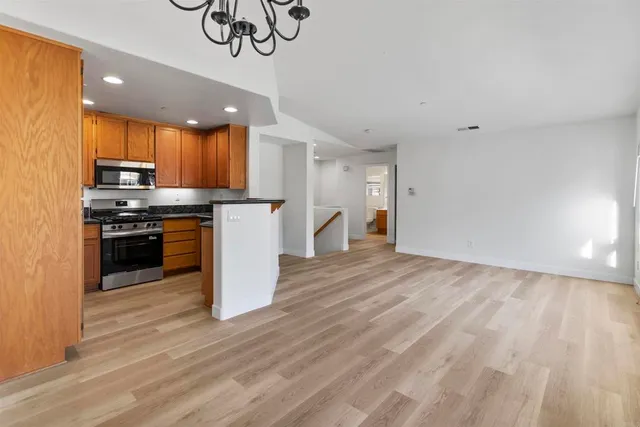 a kitchen with stainless steel appliances a stove top oven a sink cabinets and wooden floor