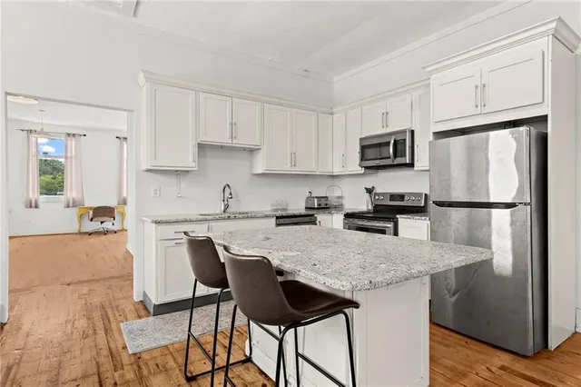 a kitchen with stainless steel appliances granite countertop a refrigerator a stove a sink a dining table and chairs