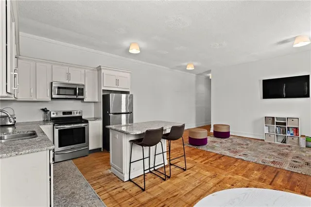 a living room with furniture a flat screen tv and kitchen view
