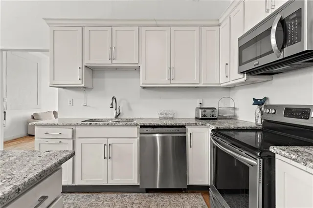 a kitchen with stainless steel appliances granite countertop a sink stove oven and white cabinets