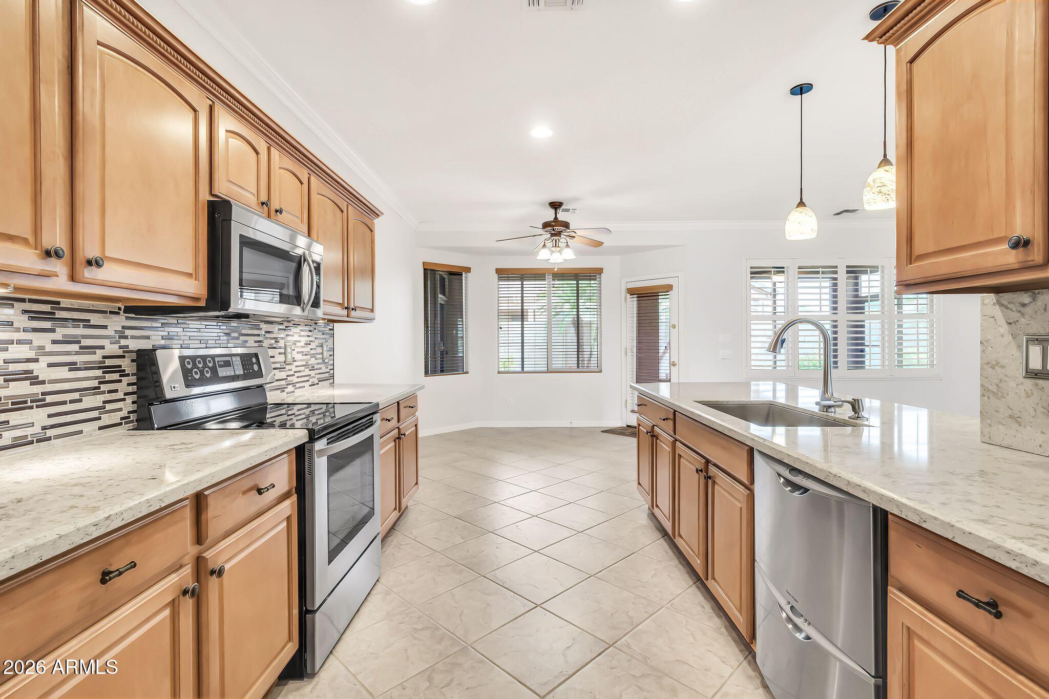 6959 South Rincon Drive Chandler, AZ 85249 - Photo 5 of 25 a kitchen with stainless steel appliances granite countertop a sink stove and cabinets