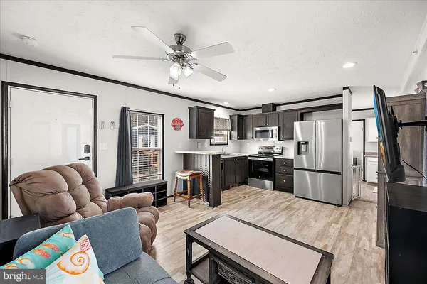 a living room with stainless steel appliances furniture and a kitchen view