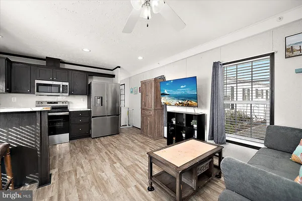 a large kitchen with stainless steel appliances kitchen island granite countertop a refrigerator a stove a sink dishwasher a dining table and chairs with wooden floor