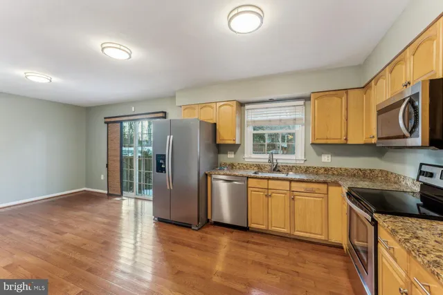 a kitchen with stainless steel appliances granite countertop a stove a sink dishwasher a refrigerator and a microwave oven with wooden floor