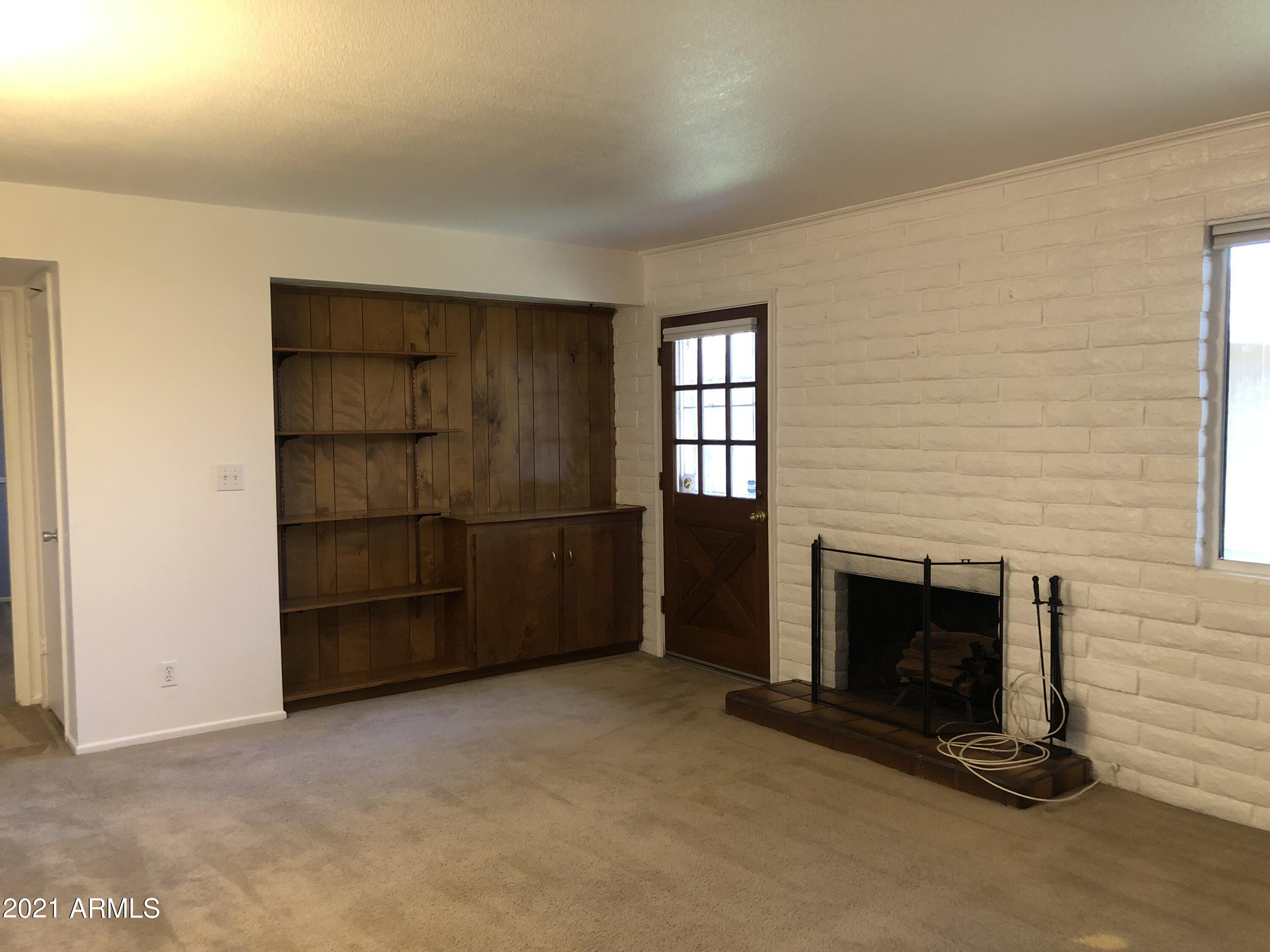 3031 South Rural Road, Unit 41 Tempe, AZ 85282 - Photo 1 of 23 an empty room with a fireplace and cabinet