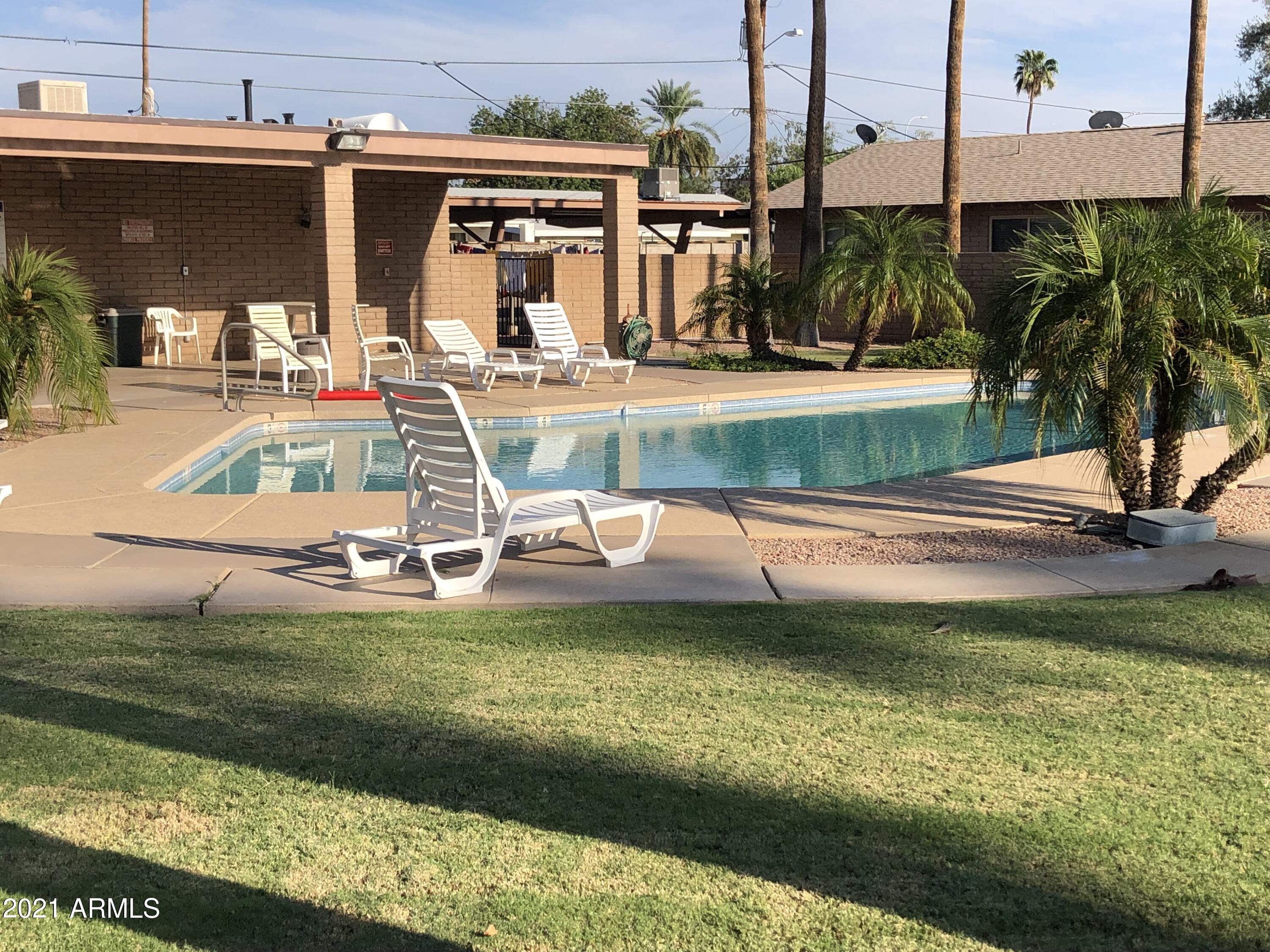 3031 South Rural Road, Unit 41 Tempe, AZ 85282 - Photo 21 of 23 a view of a swimming pool with a lawn chairs under an umbrella