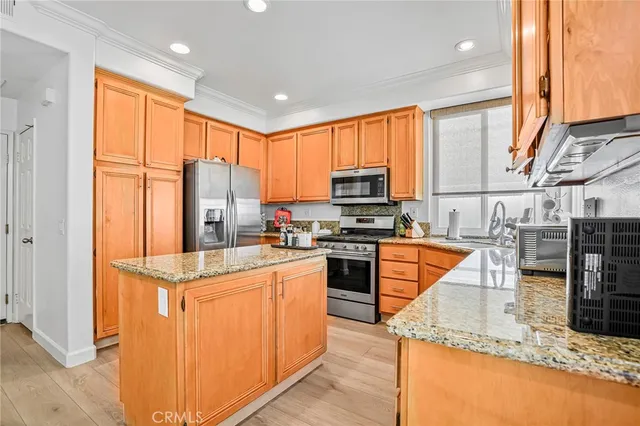 a kitchen with stainless steel appliances granite countertop a refrigerator a stove and a sink with wooden floor