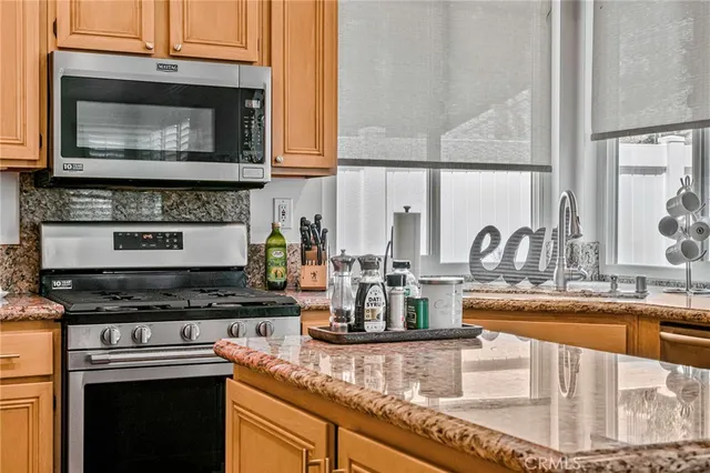 a kitchen with kitchen island granite countertop a stove and a microwave