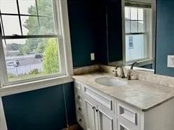 a bathroom with a granite countertop sink and a large window