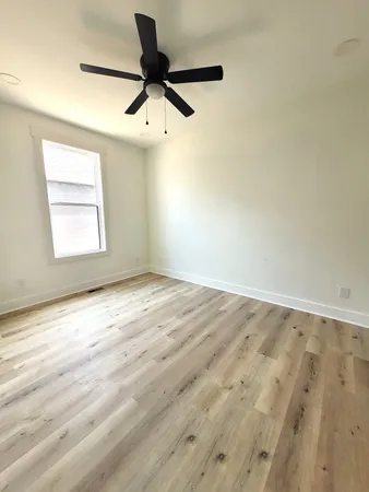 an empty room with a window and a ceiling fan