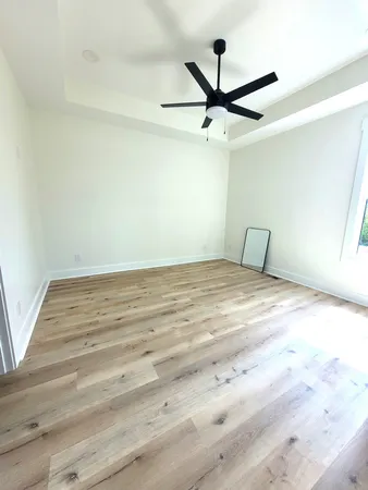 a room with a ceiling fan and wooden floor