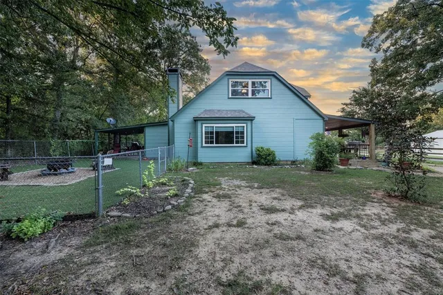a view of a house with a yard plants and large tree