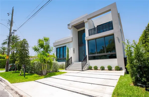 a front view of a house with a yard and potted plants