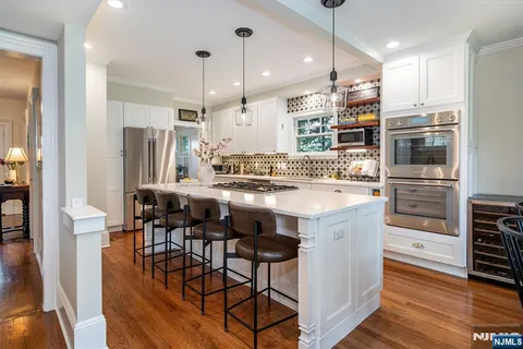 a kitchen with stainless steel appliances a dining table chairs stove and cabinets