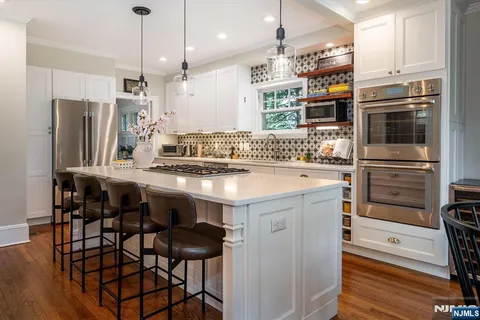a kitchen with stainless steel appliances kitchen island granite countertop a table chairs stove and refrigerator