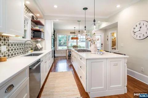 a large kitchen with kitchen island a stove a sink dishwasher a dining table and chairs with wooden floor