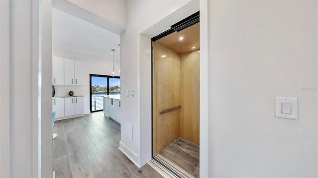 a view of a hallway with wooden floor and a bathroom