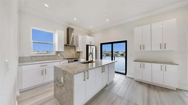 a kitchen with stainless steel appliances granite countertop a stove a sink dishwasher and a refrigerator with white cabinets