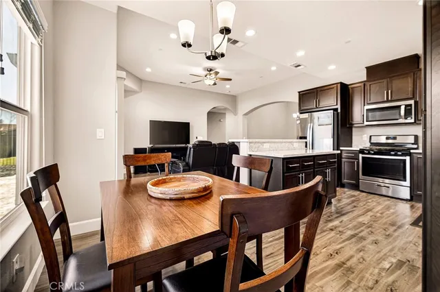 a kitchen with stainless steel appliances granite countertop a stove top oven a sink dishwasher and a refrigerator with wooden floor