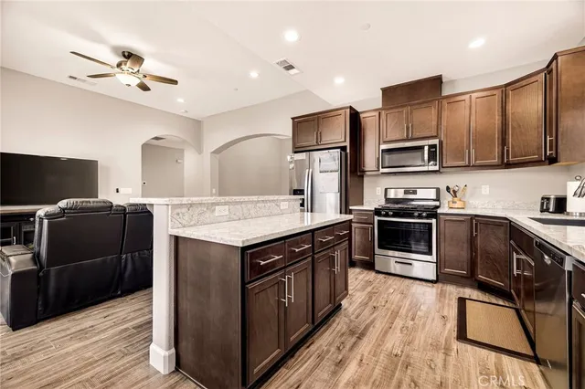a kitchen with stainless steel appliances granite countertop a refrigerator a sink dishwasher a stove top oven a refrigerator with wooden cabinets and floor